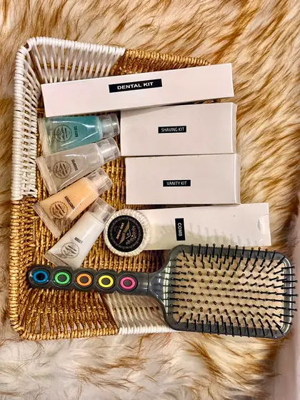 Toiletry hamper. A basket with dental kit, shaving kit, shampoo, lotions and a hairbrush.