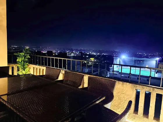 Night view over the city from a private terrace with rattan dining set