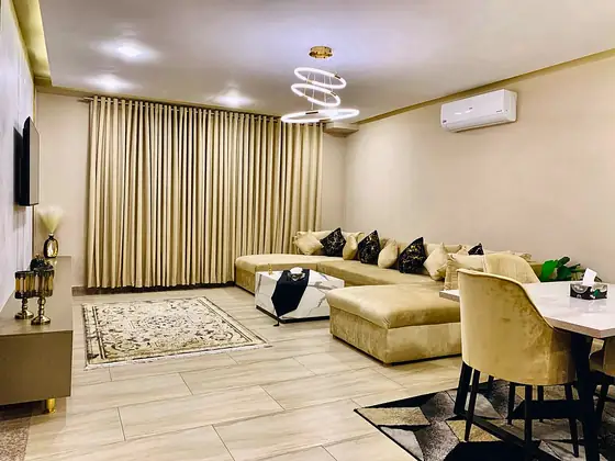 Spacious lounge with tall gold curtains, dining area, patterned rug and split AC.