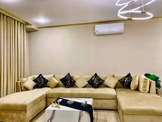 The sectional sofa with black-and-gold cushions under a halo ring light.
