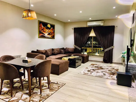Lounge and dining with velvet chairs, geometric rug, split AC and balcony curtains.