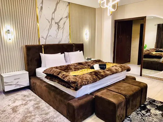 The bed from the side: fur throw, white bedside tables and marble-look panel.
