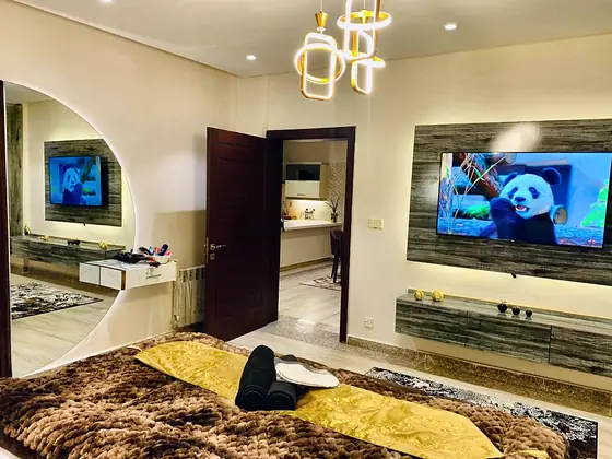 Bedroom TV on a feature wall, round arched mirror and fur throw.