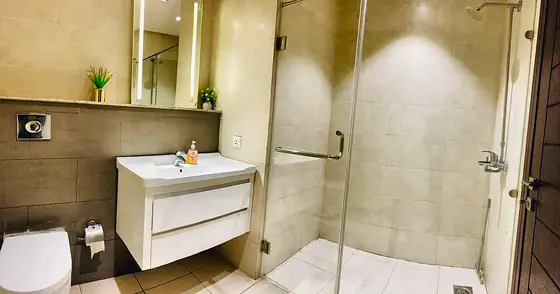 Bathroom with glass shower, floating vanity and a mirror lit by LED strips.