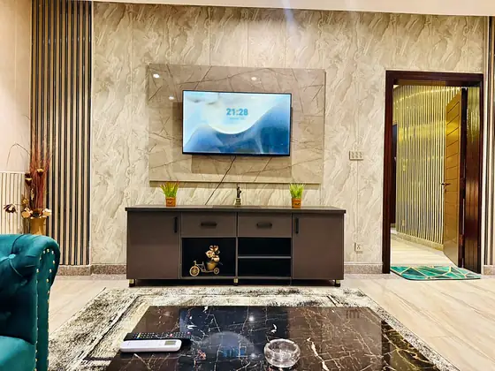 TV console with marble-look coffee table in front, framed by a slatted wood panel.