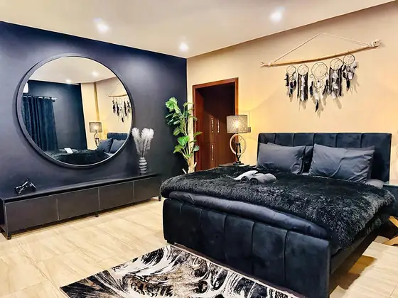 Master bedroom with a black velvet bed and faux-fur throw, round mirror and dream-catchers.
