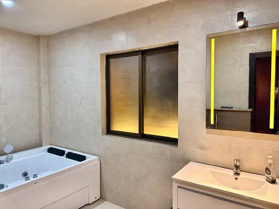 Bathroom with a whirlpool jacuzzi tub, vanity and LED-lit mirror.