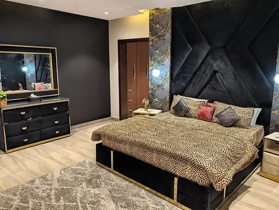 The leopard-print bedroom with a black-and-gold dresser, mirror and patterned rug.