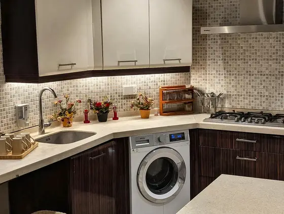 Corner kitchen with sink, washing machine, gas hob, dish rack and mosaic splashback.