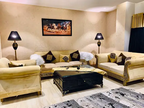 Cream velvet seating with black cushions, lamps and a patterned rug.