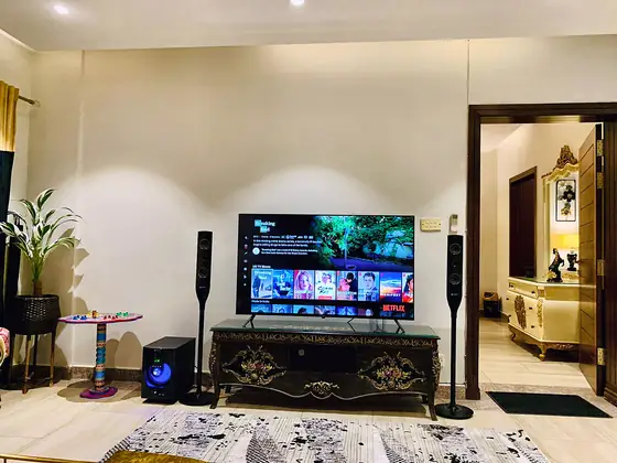 TV area with smart TV, floor-standing speakers, subwoofer and a hand-painted truck-art side table.