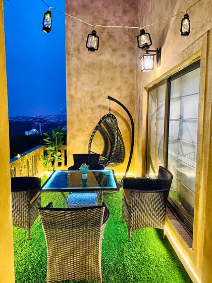 Terrace with lantern string lights, rattan seating and a hanging egg chair.