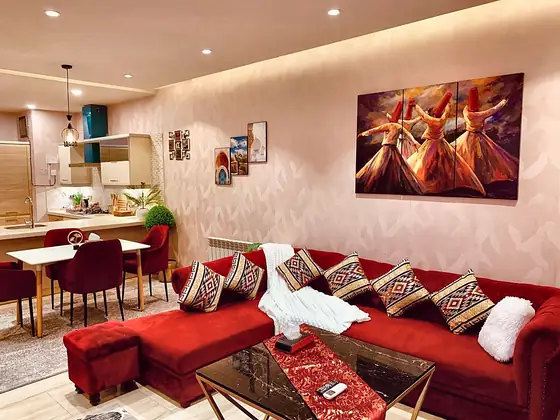 Lounge and dining side by side: velvet seating, dining table with crimson chairs, pendant lights and an open kitchen.
