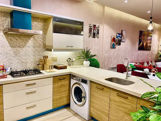 Kitchens ready for a real stay. Gas hob, extractor chimney, sink with mixer tap and a built-in washing machine, with a kettle, snacks and a stocked fridge.