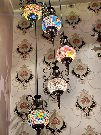 Hand-made Turkish mosaic lanterns hanging against damask wallpaper.