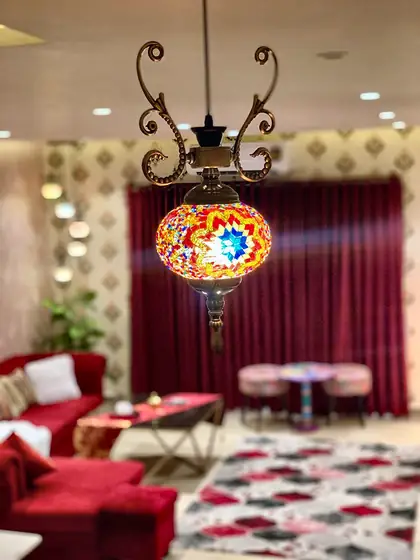 Mosaic pendant lantern over the lounge with crimson velvet curtains.