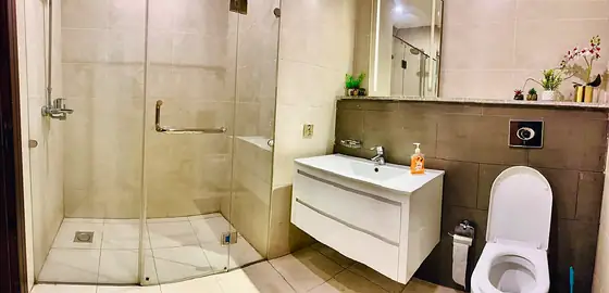 Bathroom with frameless glass walk-in shower, floating white vanity and wall-hung toilet with bidet spray.